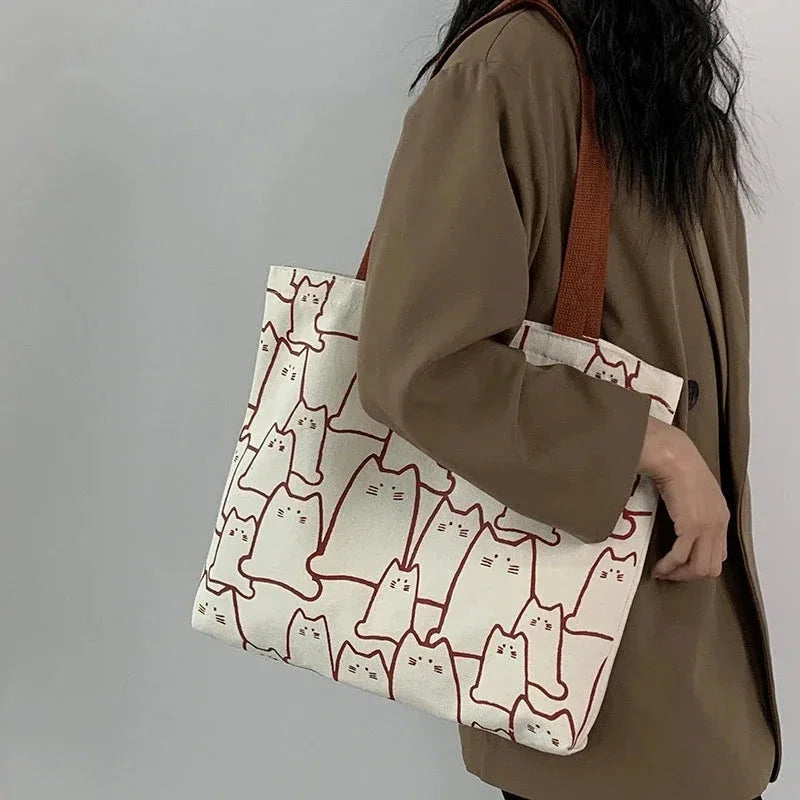 Person holding a tote bag with cat pattern against a plain background