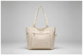 Beige tote bag on denim jacket with phone and clear glass bottle