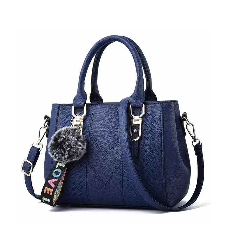Blue handbag with a decorative keychain on a white background