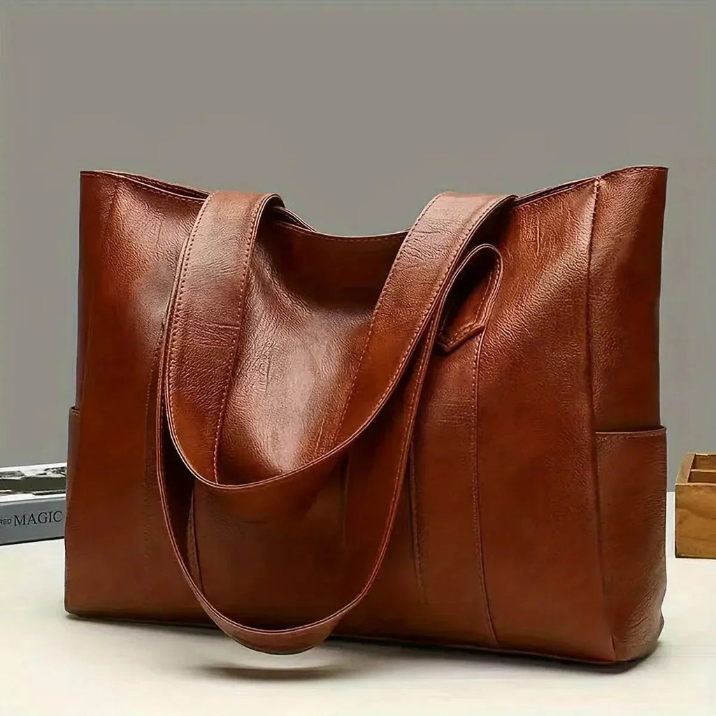 Brown leather tote bag on a light gray background
