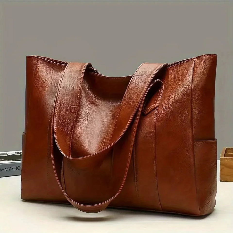 Brown leather tote bag on a light gray background