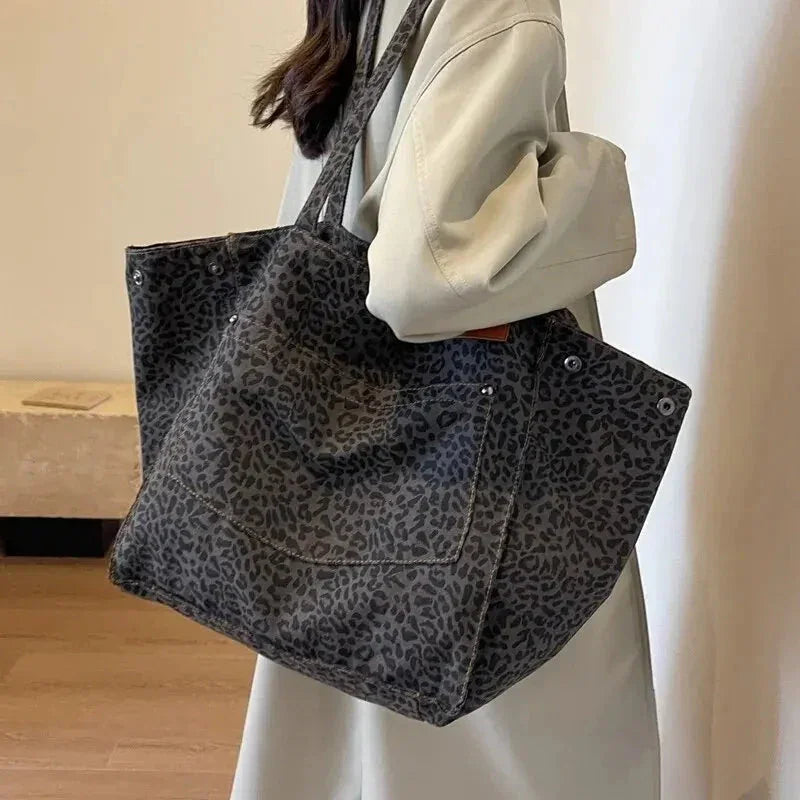 Person holding a leopard print tote bag indoors