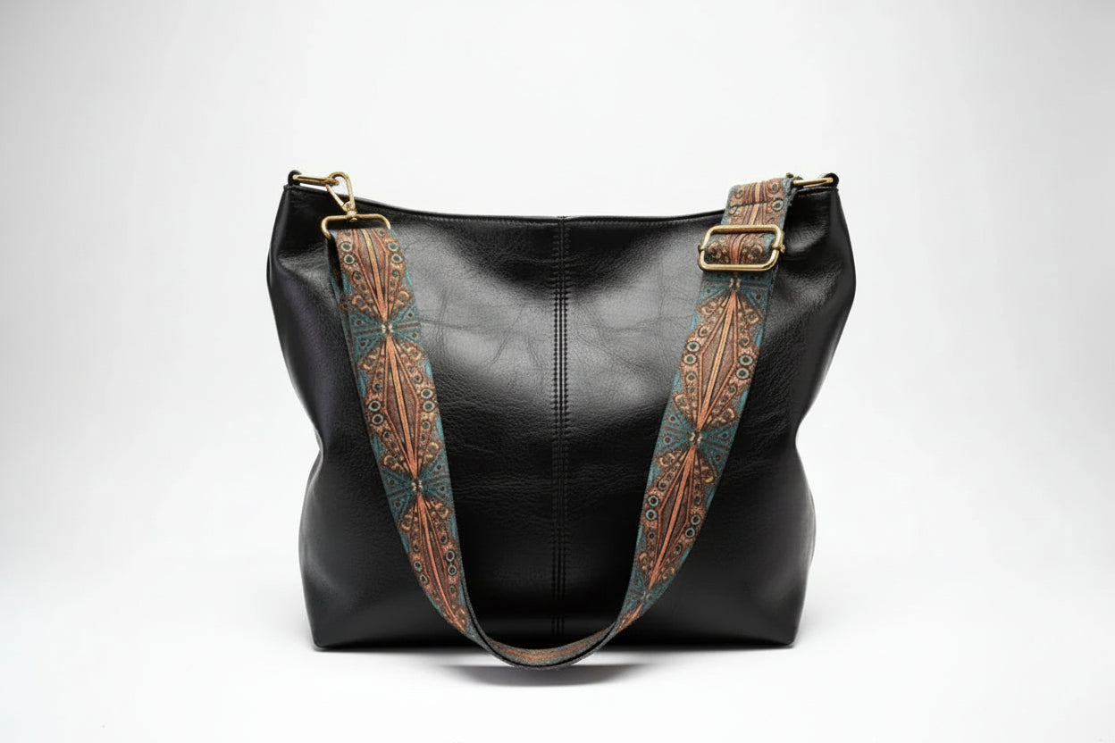 Black leather handbag with decorative brown straps on a white background