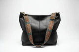 Black leather handbag with decorative brown straps on a white background