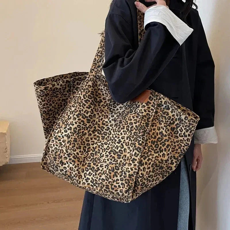 Person holding a leopard print tote bag against a plain background