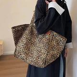 Person holding a leopard print tote bag against a plain background