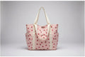 Pink tote bag with strawberry pattern on a surface near a window.
