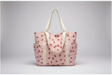 Pink tote bag with strawberry pattern on a surface near a window.