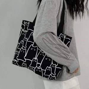 Person holding a tote bag with cat pattern against a plain background