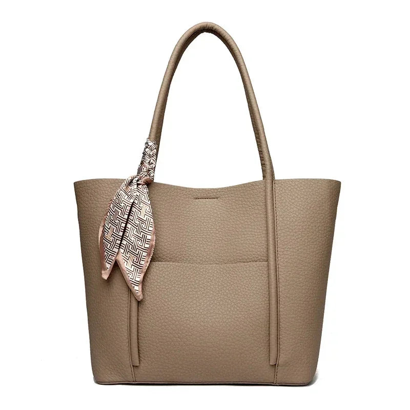 Beige handbag with a patterned scarf draped over the handle on a white background