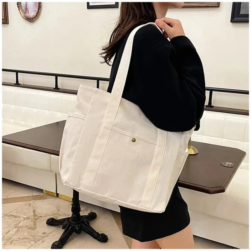 Person holding a white tote bag in an indoor setting