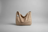 Beige corduroy handbag with a small white cat plushie on a surface with blinds in the background