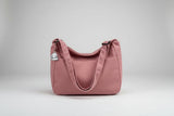 Pink corduroy bag with a patch on a bed