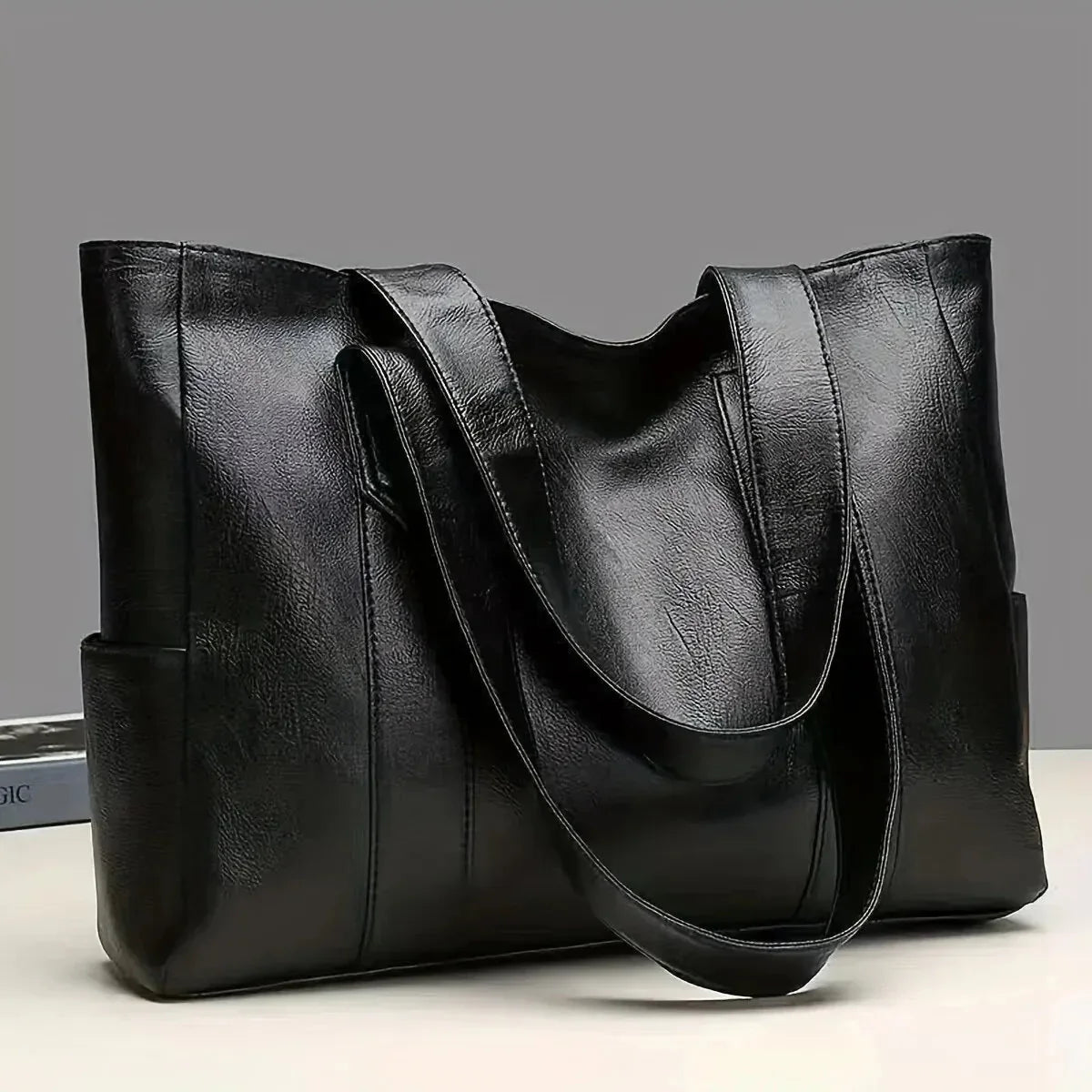 Black leather tote bag on a light gray background
