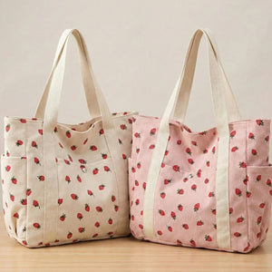 Two tote bags with strawberry pattern on a wooden surface