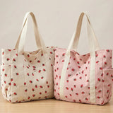Two tote bags with strawberry pattern on a wooden surface