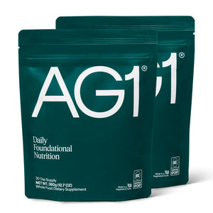 AG1 supplement package with a bottle and scoop on a white background
