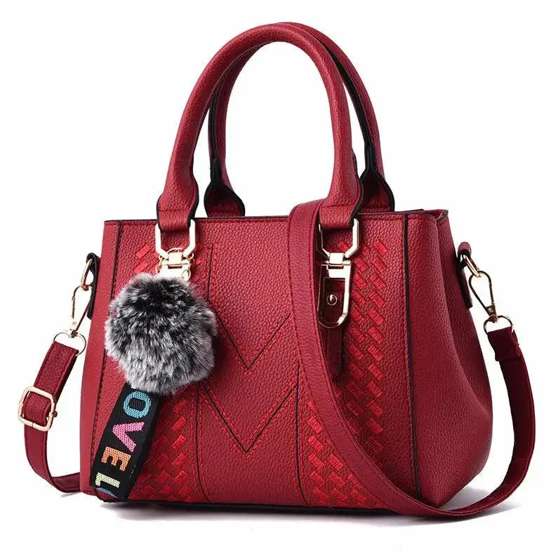 Red handbag with a fur pom-pom and colorful strap on a white background